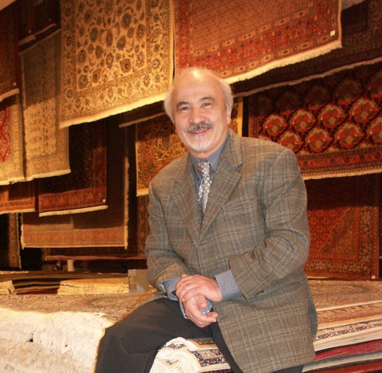 Houschang Farhadian sitzt auf Orientteppichen